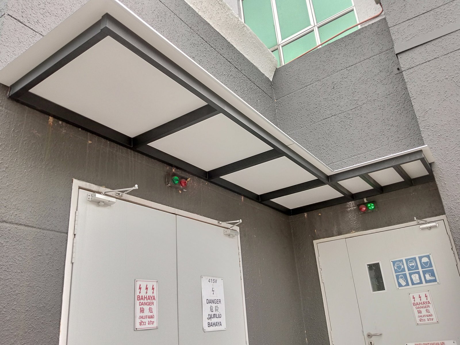 Completed flat panel awning with a dark steel frame above commercial service doors.